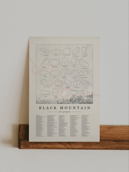 A cream color, customized rock climbing ticklist poster for the Black Mountain rock climbing location in San Jacinto Mountain, California. The design has an overlay of crag topography, nature landscapes, and traced boulders, the person's name, and a list of bouldering problems at the bottom. Displayed as wall art in a living room.