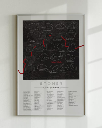 A black color, customized rock climbing ticklist poster for the Buttermilks rock climbing location in Topanga, California. The design has an overlay of crag topography, nature landscapes, and traced boulders, the person's name, and a list of bouldering problems at the bottom. Displayed as wall art in a living room.